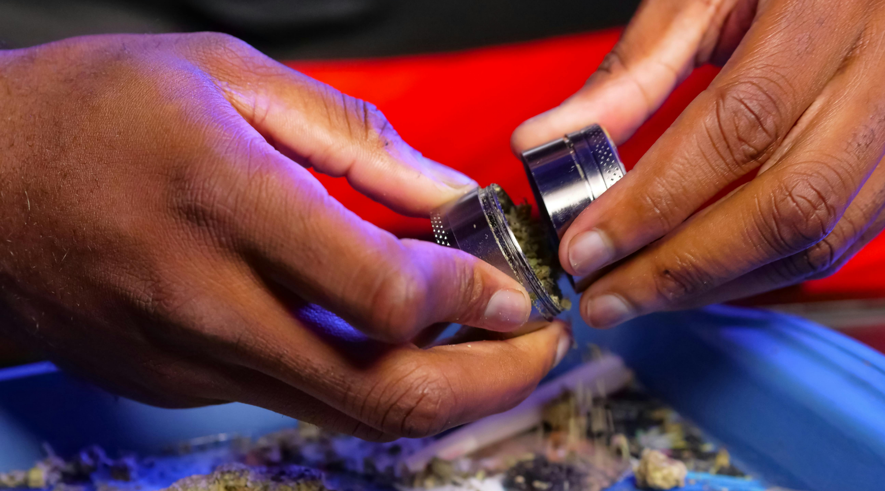 Close-up of hands opening a herb grinder, showing built-up residue—illustrating the need for regular maintenance and how to clean a grinder effectively.