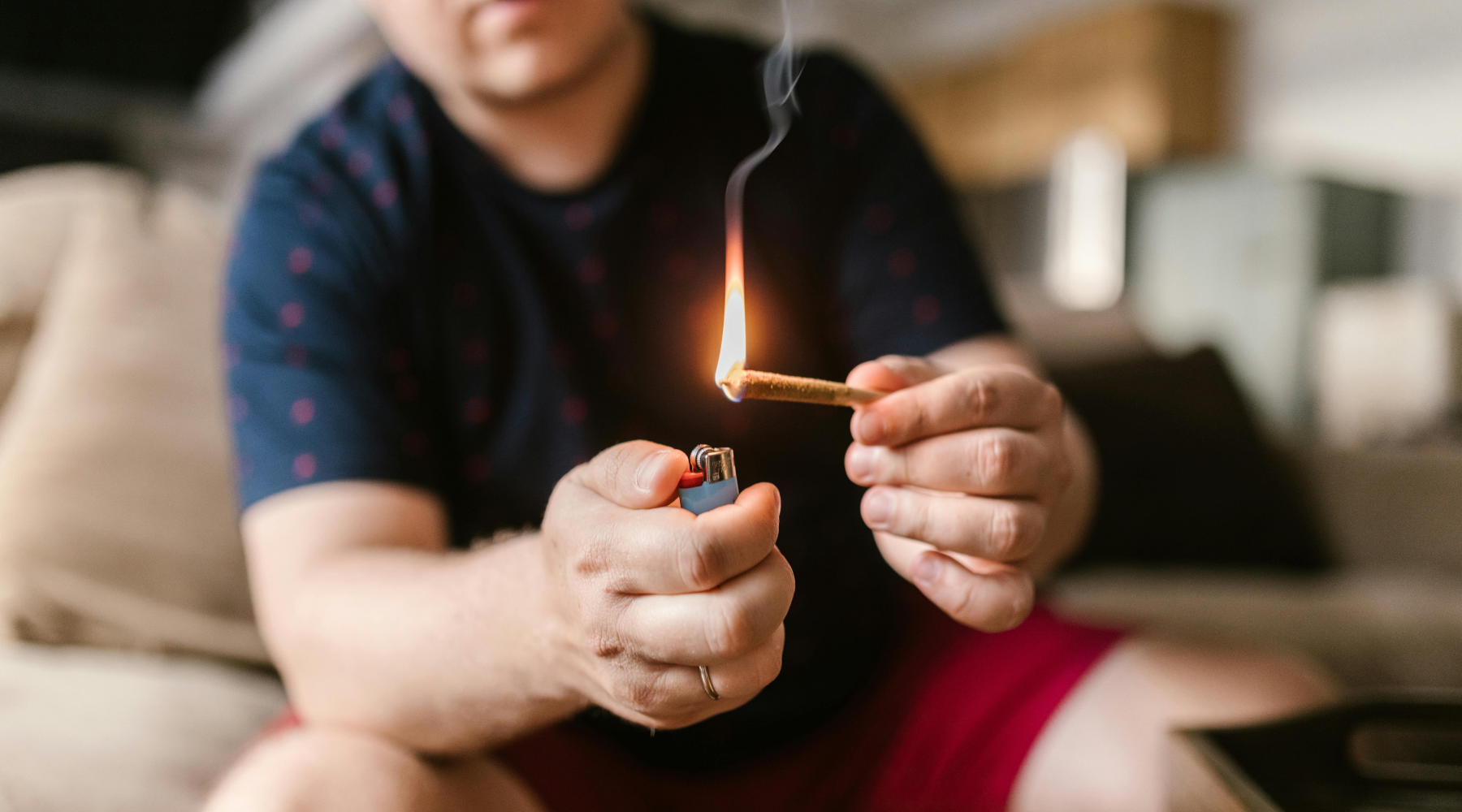 Person lighting a pre-rolled cone indoors, representing the convenience and ease of buying pre-rolled cones for quick, mess-free sessions.