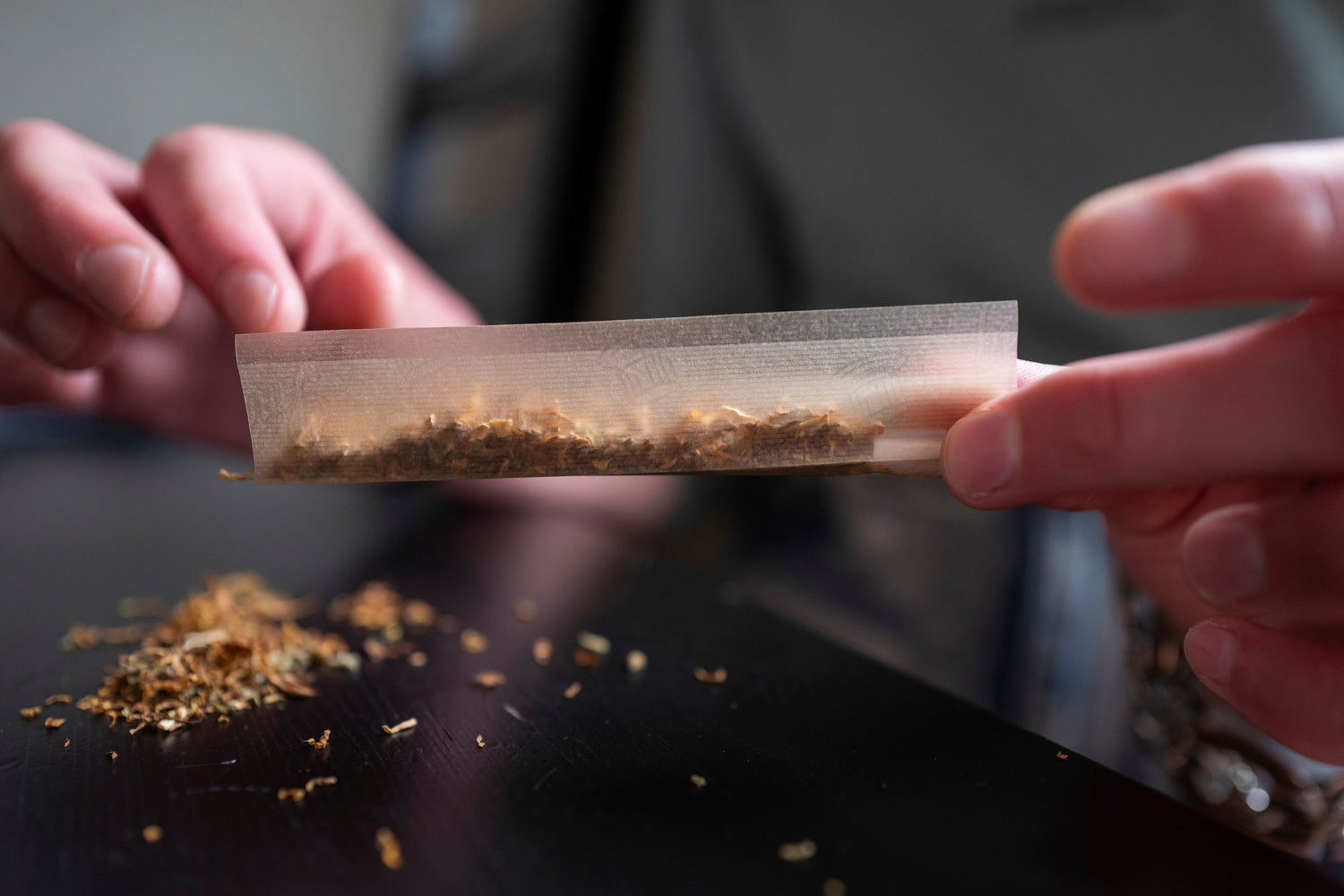 Close-up of hands rolling shredded tobacco into a cigarette using thin rolling paper, illustrating how paper design influences airflow, burn consistency, and overall smoking experience.