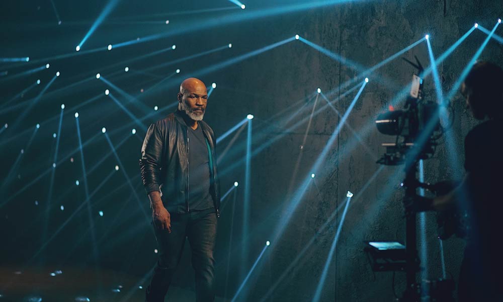 Mike Tyson on set with dynamic light beams, promoting the Futurola x Tyson rolling collection.